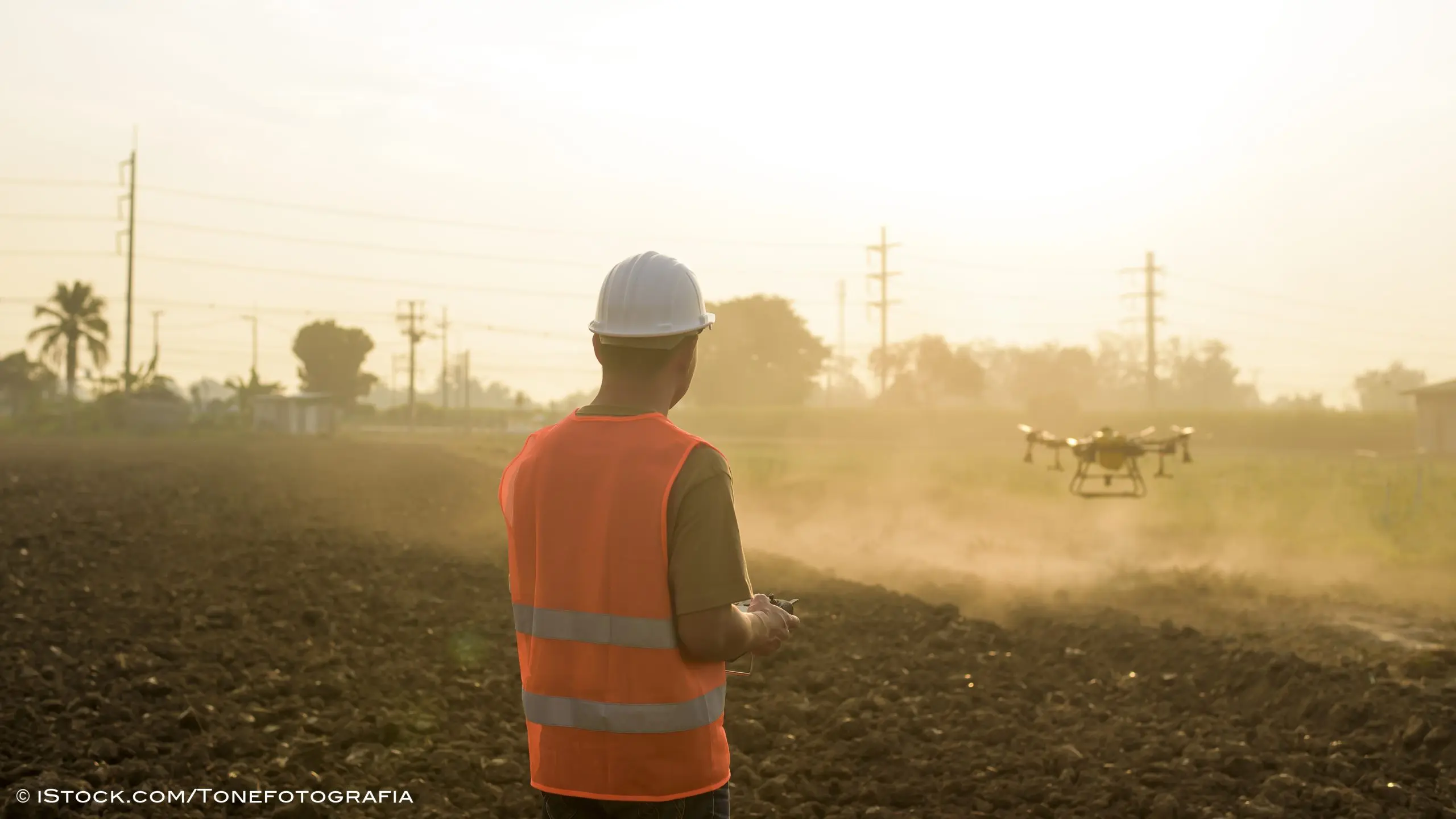 Male engineer controlling drone spraying fertilizer and pesticide over farmland,High technology innovations and smart farming